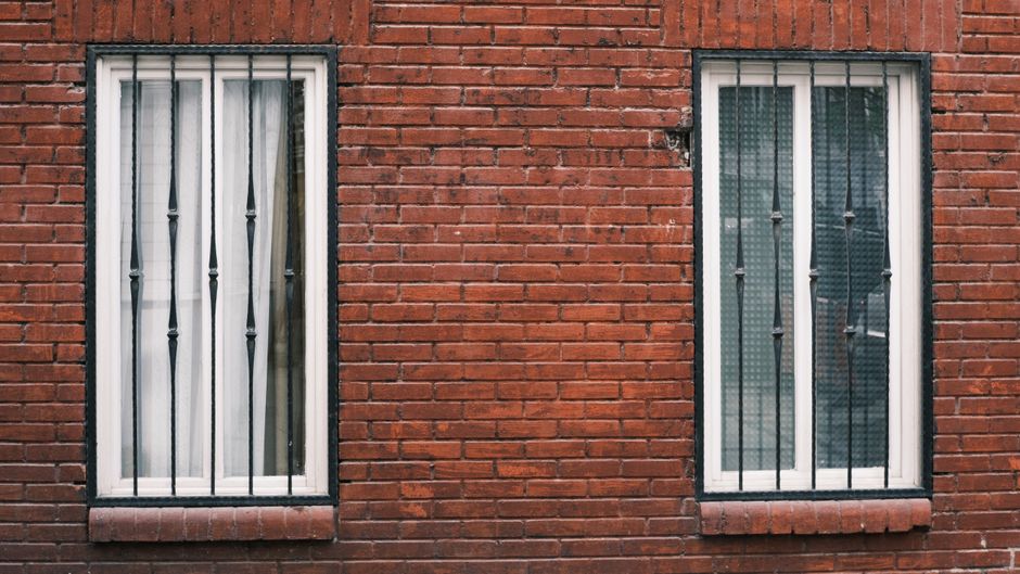 Red brick wall with two windows.