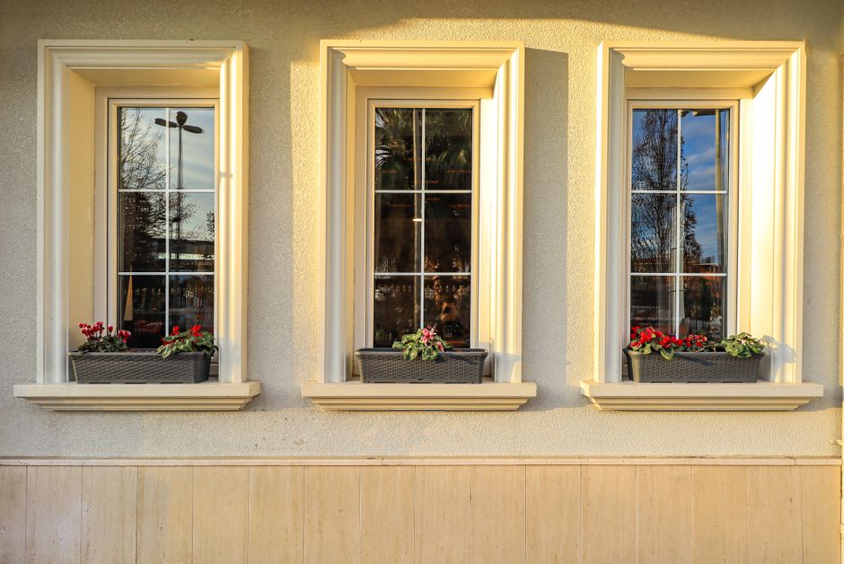 Building front with three windows and flowerpots on the sills.
