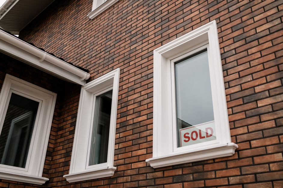 Close-up of a brick house wall with a window set in it.