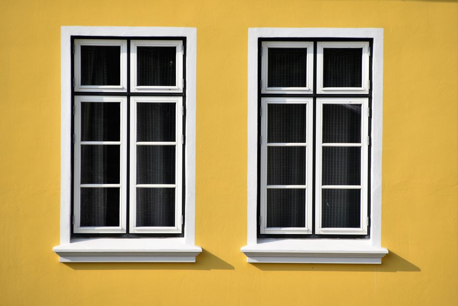 Two white-framed windows on the front wall of a house.
